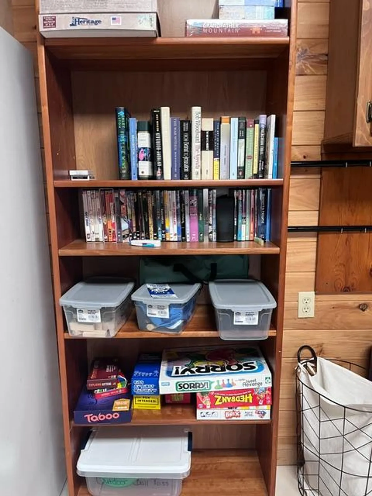 A warm and nostalgic nook lined with a bookshelf full of books and board games, plus storage bins for easy access to entertainment. The area invites guests to engage in friendly competition or discover a new favorite book on a rainy day.