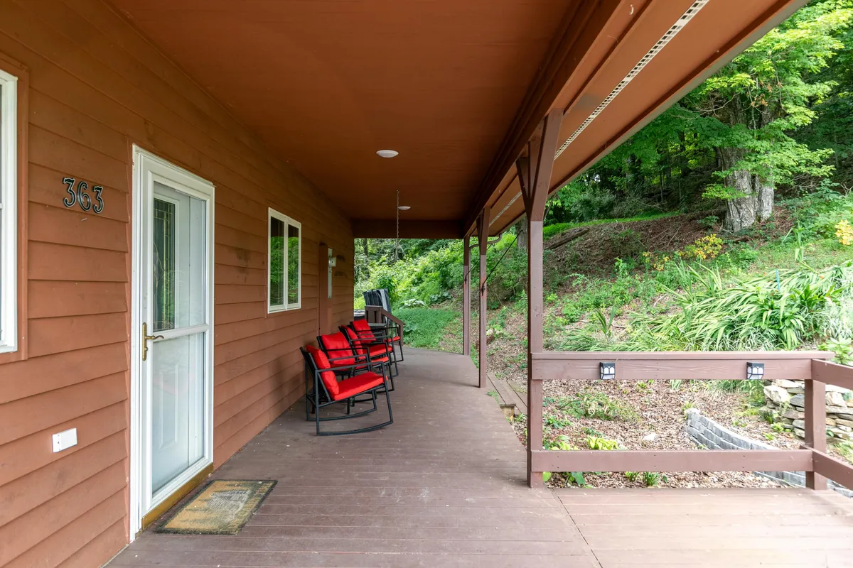 A welcoming wooden porch with red rocking chairs and greenery in the background, inviting guests to relax outdoors. The porch is spacious enough for both people and pets to enjoy fresh mountain air and scenic views, ideal for leisurely afternoons after a walk.
