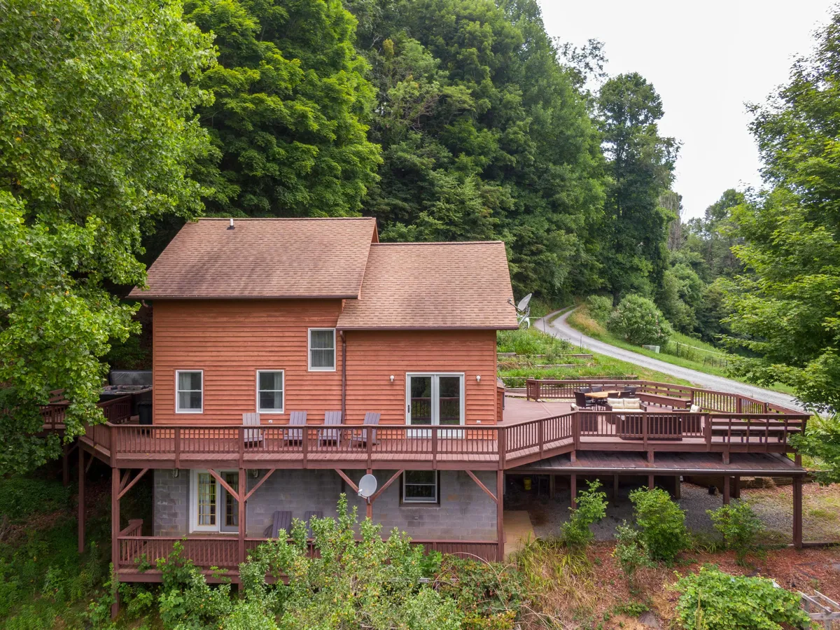 A serene wooden deck surrounded by lush trees, with ample space for outdoor dining and relaxation. The view offers a seamless transition from the indoors, promising peaceful mornings and stunning sunset experiences.