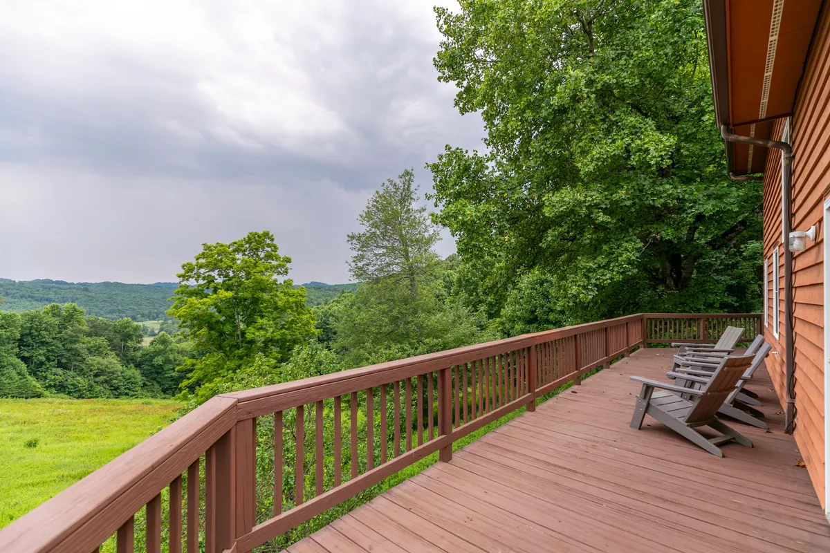 This image shows a spacious wooden deck outfitted with reclining chairs, overlooking lush greenery and distant rolling hills. The setting exudes tranquility and invites guests to soak in the panoramic mountain views, making it ideal for morning coffee, sunset watching, or simply relaxing after a day of adventure.