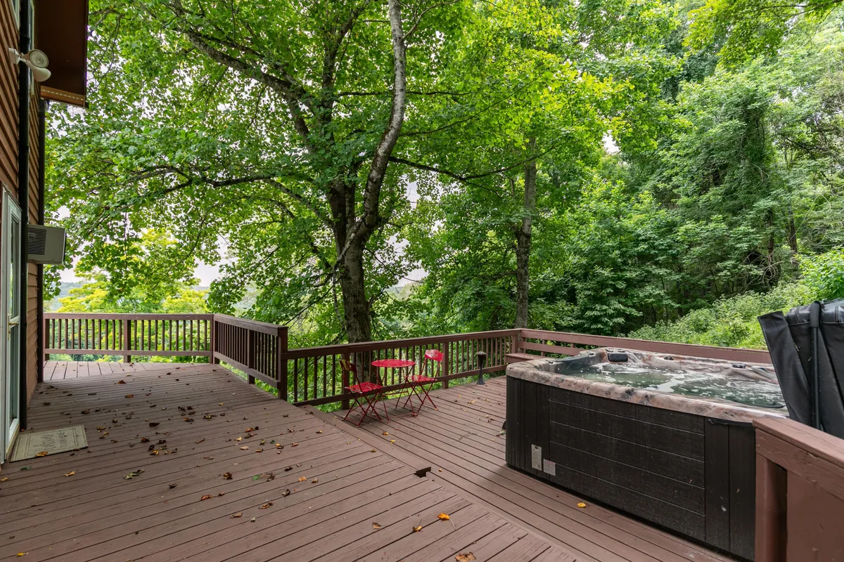 This image spotlights a serene outdoor area featuring a brand new hot tub surrounded by lush greenery and a red bistro set, suggesting a comfortable place to unwind after outdoor adventures. The secluded ambiance and fresh air make it ideal for relaxing while a pet lounges nearby.