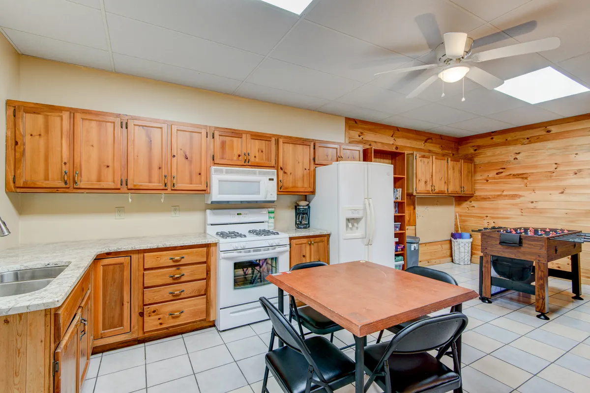 A homey kitchen and dining area with wooden cabinets, white appliances, and a dining table, offering a warm atmosphere for group cooking and dining together.
