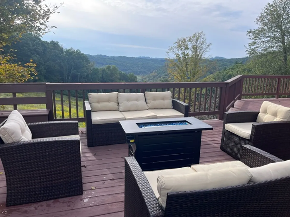 This exterior view features a cozy outdoor seating area and a fire pit with a stunning scenic outlook over the hills. The setting is perfect for gathering with friends, watching the sunset, or enjoying a quiet moment in nature.