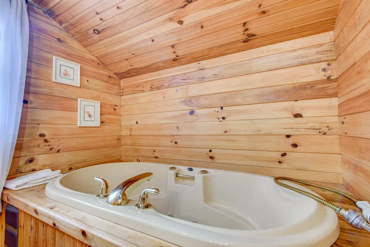 This interior bathroom image displays a whirlpool tub set against wooden walls and framed artwork. The mood is tranquil, inviting moments of solitude and self-care.